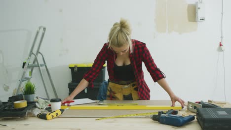 mujer midiendo láminas de madera contrachapada con nivel de burbuja