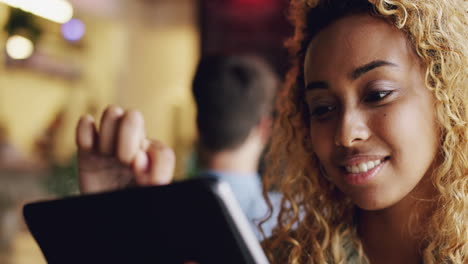 Mixed-race-teenager-using-ipad-tablet-computer-touchscreen-in-cafe