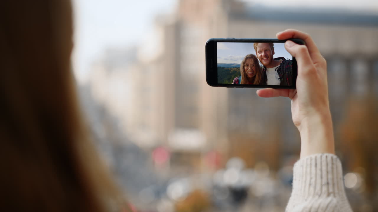 Amigos despreocupados em videoconferência. Close da mão de uma garota segurando um smartphone
