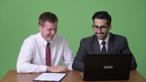 two young multi-ethnic businessmen working together against green background