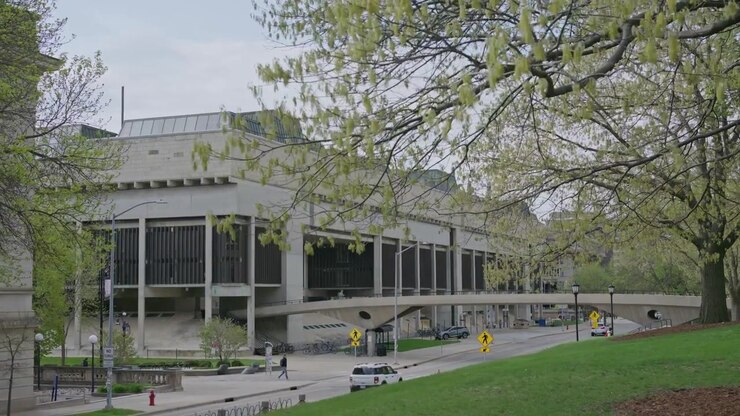 Tomada cinematográfica de dolly com gimbal da estrada do campus da Universidade de Wisconsin, levando a uma ponte para pedestres, com movimento suave e estabilizado ao ar livre.