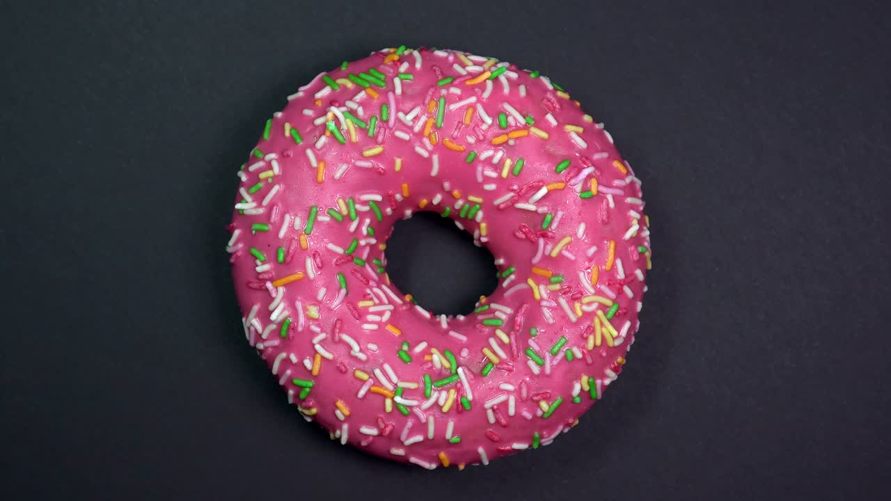 saboroso y fresco rosquilla rosquilla macro disparo de primer plano girando sobre un fondo negro.