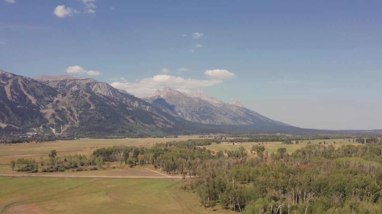 Ripresa aerea con drone delle Grand Tetons dal Snake River Ranch a Jackson, Wyoming. Vista diurna della valle che guarda verso le montagne. Tilt down. Girato in 4K.
