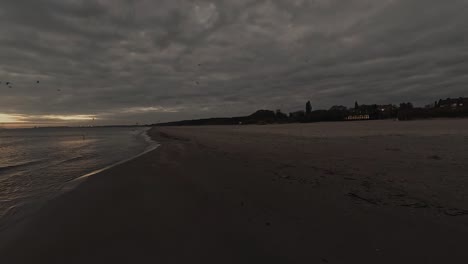 dark moody clouds and city beach shore with calm sea at the cold autumn morning