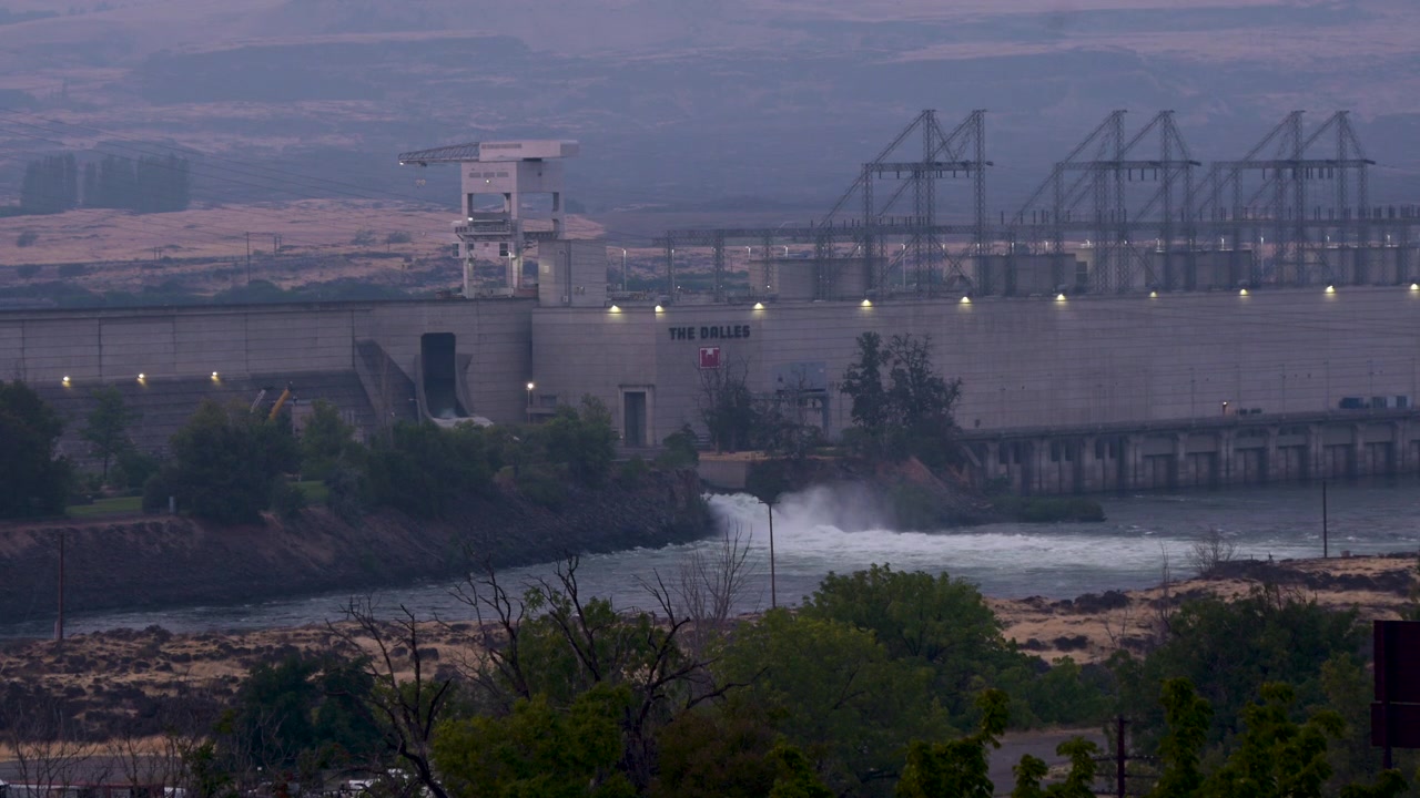 La diga The Dalles sul fiume Columbia in Oregon, con l'acqua che scorre attraverso l'impianto idroelettrico mentre il fumo degli incendi boschivi avvolge il paesaggio circostante