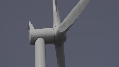 close up of wind turbine head spinning with blue sky background