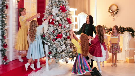 group of girls decorate christmas tree in studio. holidays and celebration concept.