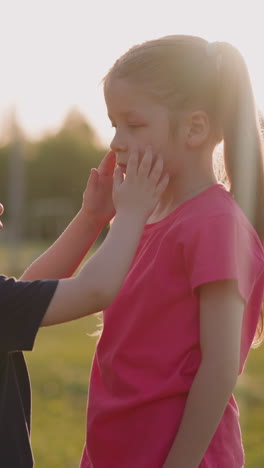 little brother strokes face of upset sister with injured eye at countryside closeup slow motion. love and care of children. support in family