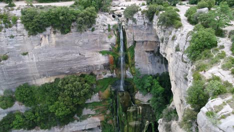 aerial view pull back away from rocky cliff edge waterfall cascading down steep drop