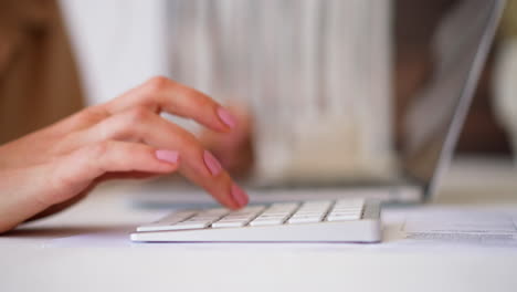 Woman-uses-white-numeric-keyboard-for-making-calculations