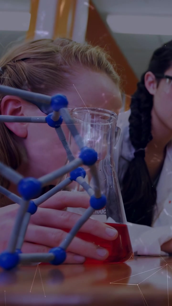 Vertical video: Student inspecting flask in lab on prompt, labels around flask analyzing red liquid