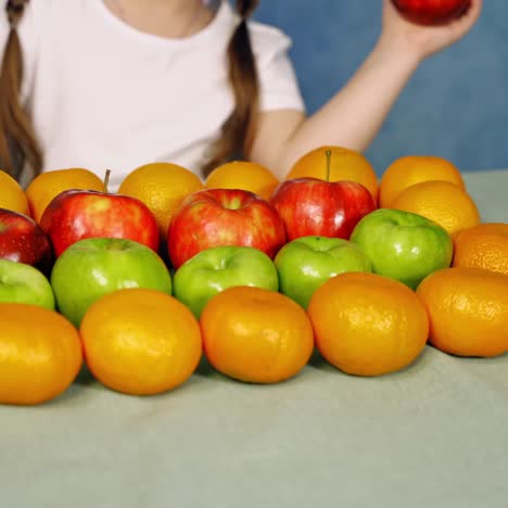. close up of fruits on table. girl sitting at table with fresh fruit