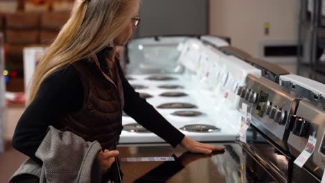 Mujer-Bastante-Madura-Girando-Las-Perillas-De-Una-Estufa-En-Una-Tienda-De-Electrodomésticos-De-Cocina