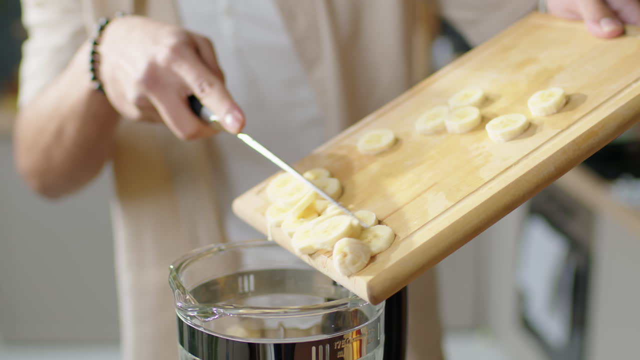 Man Putting Banana into Blender before Making Smoothie