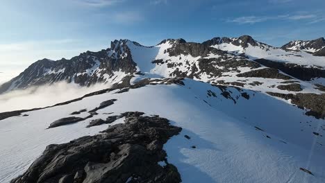 fpv drone footage gliding above a snowy landscape among amidst the mountains in nothern norway