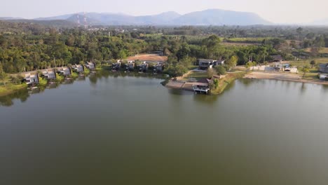 aerial drone footage over a lake with tilt down and dolly movement of a hotel and resort in thailand