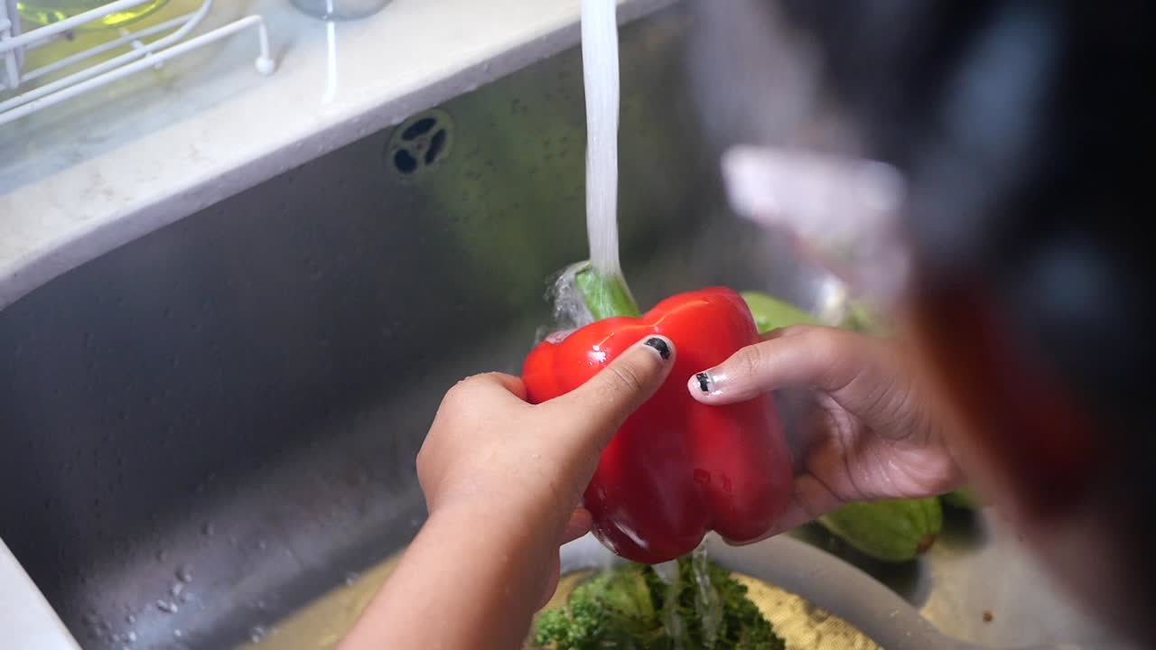 Washing a red pepper in the sink