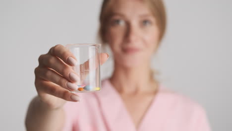 caucasian female doctor holding flask with pills.