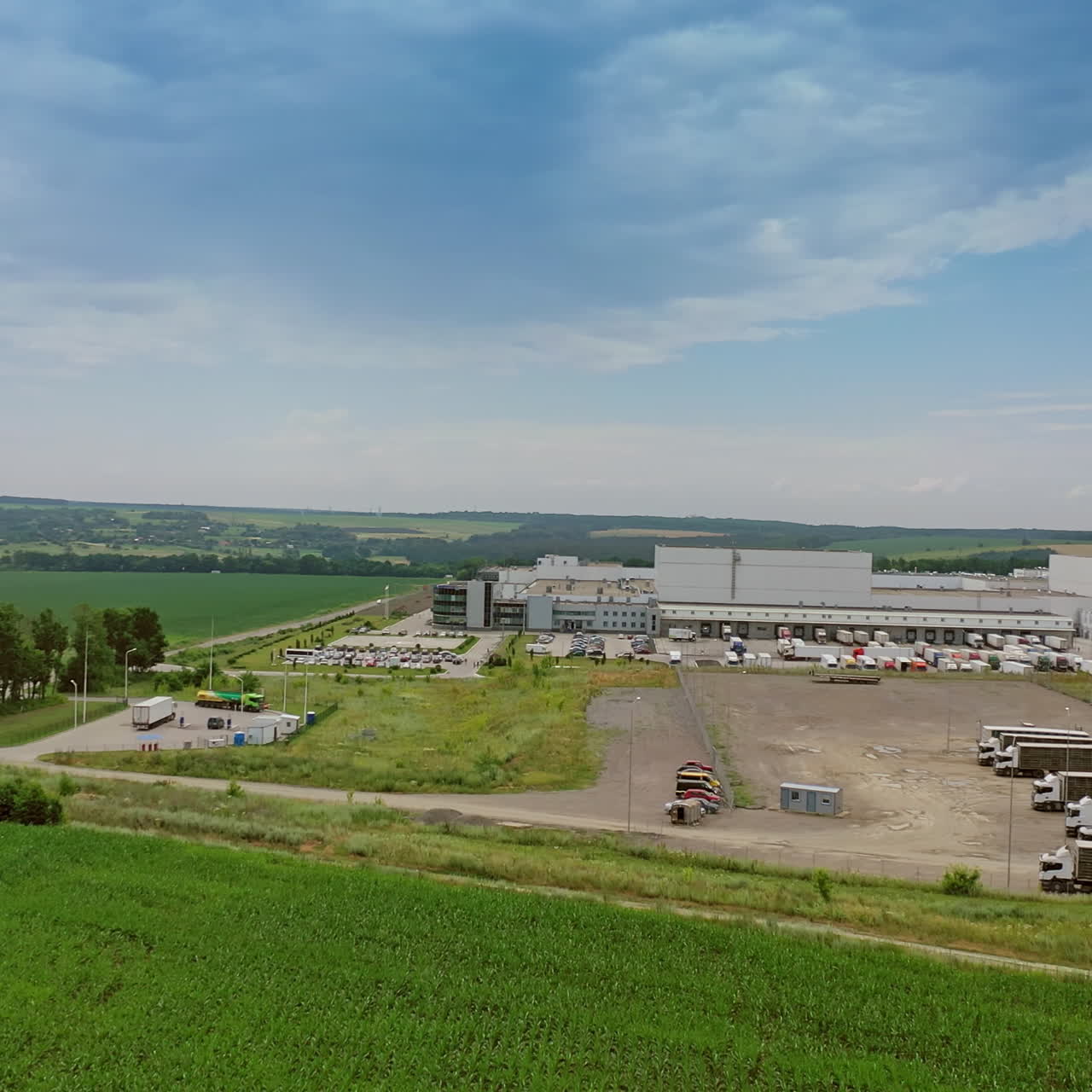 Parking place for trucks near industrial complex outdoors. Side view of the modern manufacturing territory on the natural green background.