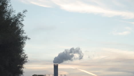 Tilt-down-from-cloudy-sky-to-smoking-factory-chimney---wide