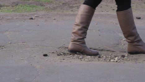 Wheels-of-baby-strolley-moving-on-broken-asphalt-road,-close-up-view