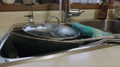 kitchen tap water running over dirty dishes in sink