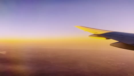 aircraft wing passing by stunningly beautiful sunset or sunrise at high cruising altitude