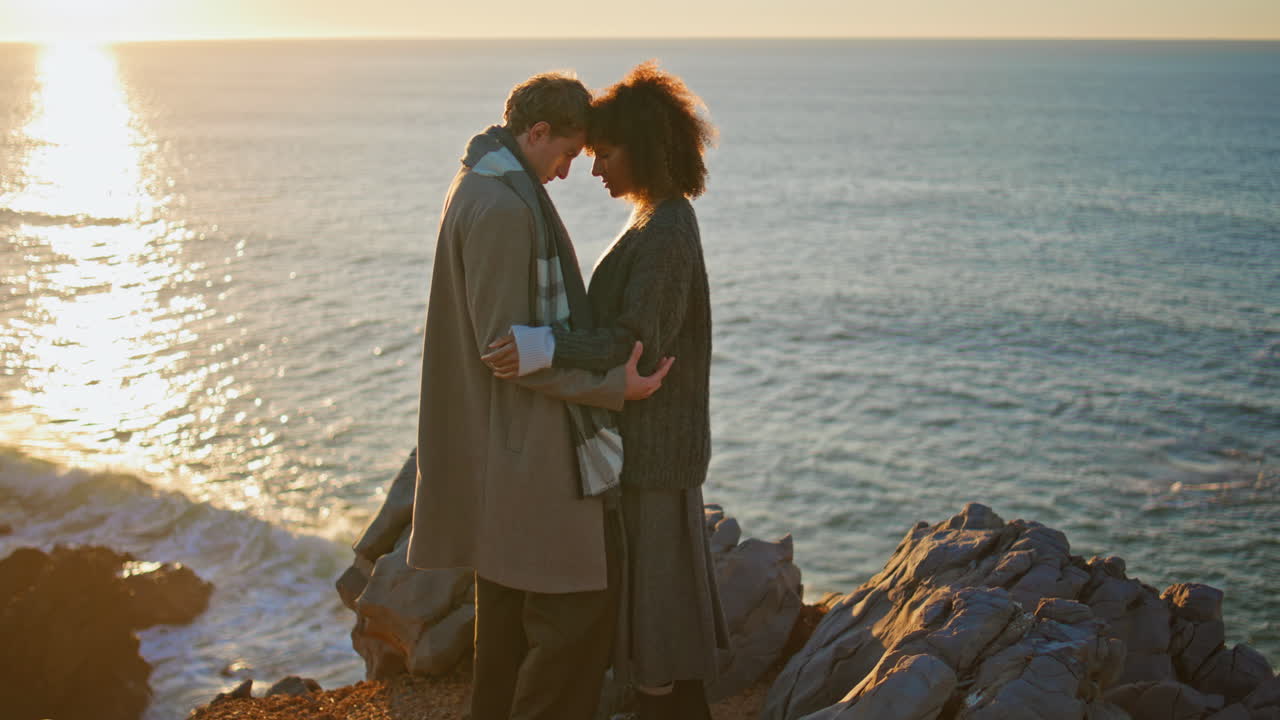 Loving pair bonding sunset coast hill. Diverse couple enjoying moment together