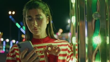 teen girl making call in neon luna park closeup. pretty girl talking phone