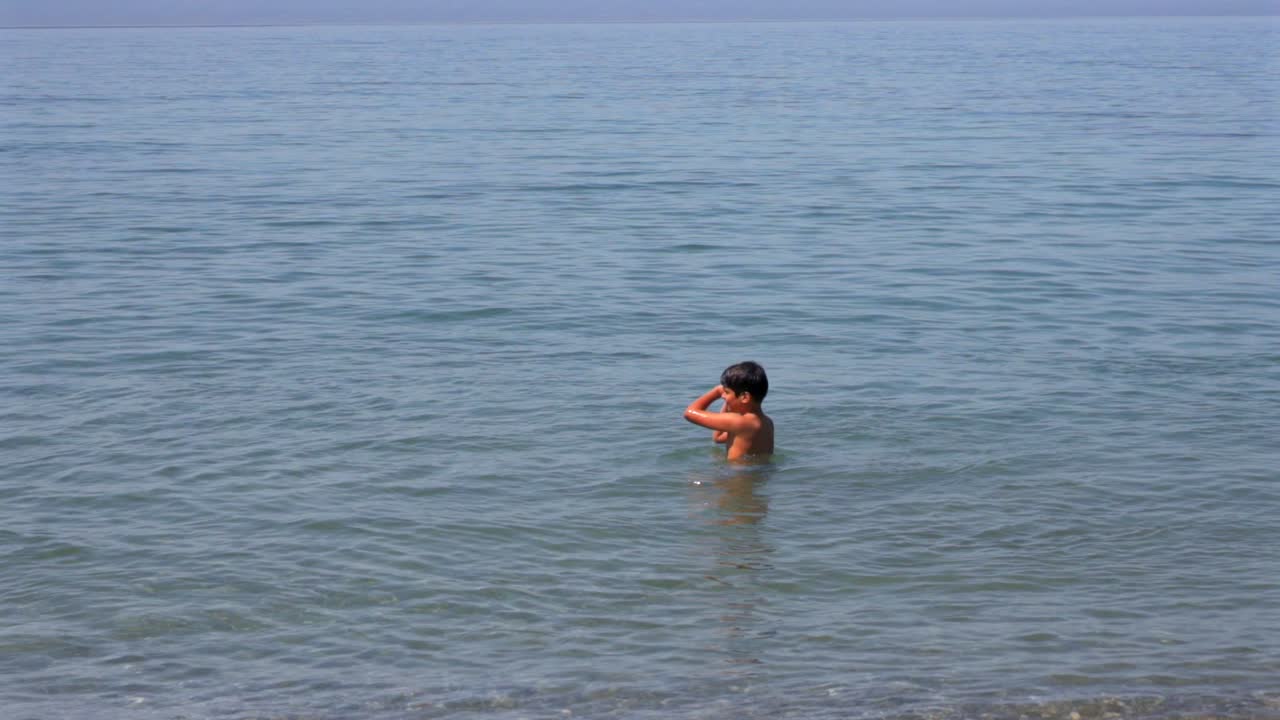 Slow motion 100fps footage of two caucasian brothers , playing with a small beach ball at sea of Kalamata, left pan medium shot