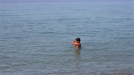slow motion 100fps footage of two caucasian brothers , playing with a small beach ball at sea of kalamata, left pan medium shot