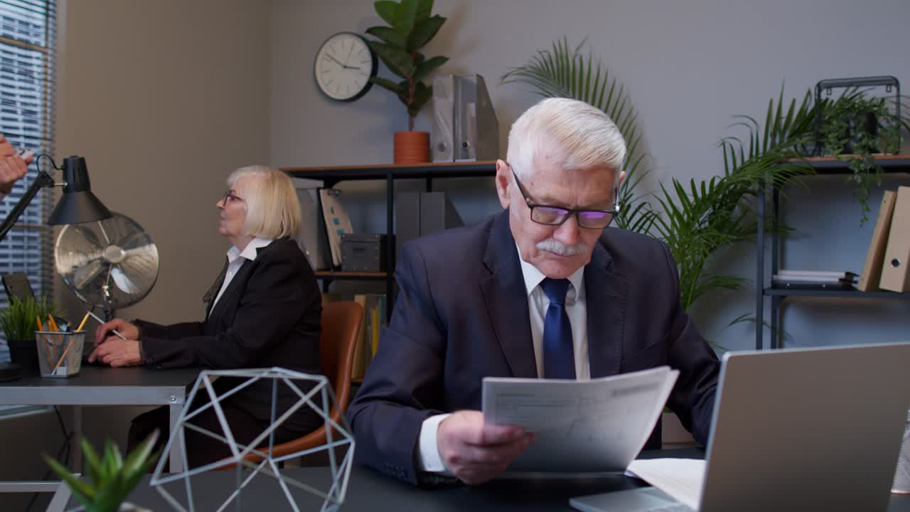 Senior elderly business company manager sitting at office reading candidate resume, job interview