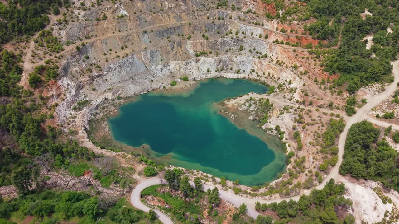 Aerial orbit around a striking lake formed in an abandoned quarry in North Evia, surrounded by rugged terrain and raw natural beauty