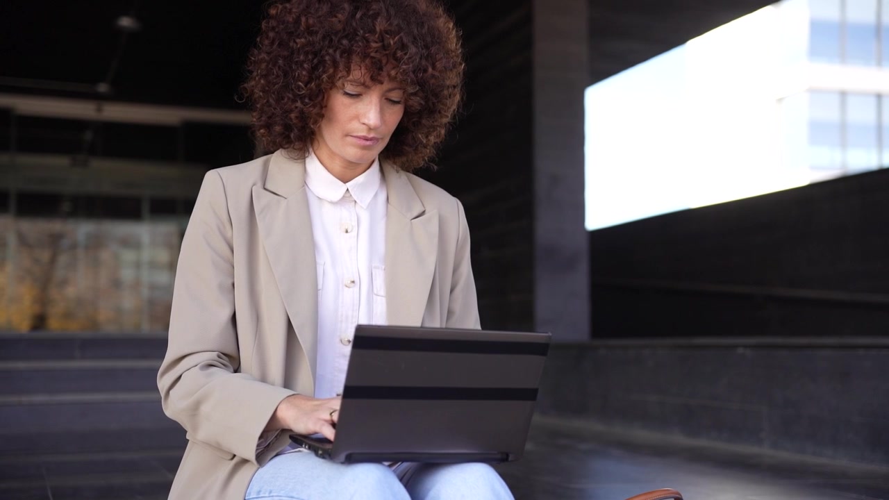 A focused and dedicated professional engaged in work outdoors utilizing a laptop computer