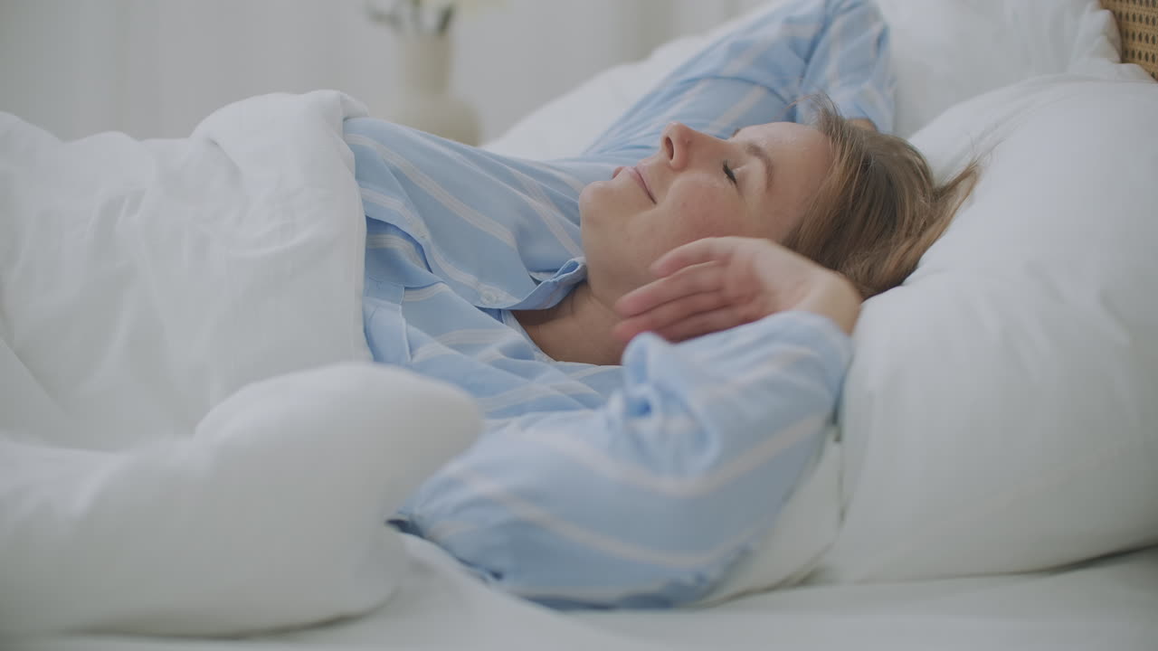 A close-up of a beautiful young woman's face. She is awakening after the sleep. Her hair is on the pillow.