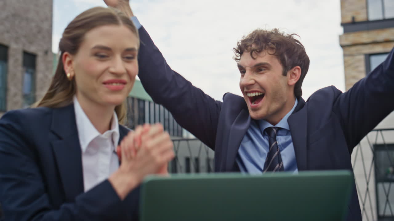 Corporate partners showing excitement looking laptop on street cafe closeup