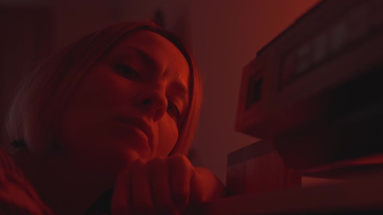 Scena contemplativa notturna. Donna con un registratore a cassette vintage. Serata tranquilla caratterizzata da introspezione e un dispositivo musicale d'altri tempi. Donna riflessiva che appoggia il mento sulla mano vicino a un classico registratore a cassette.