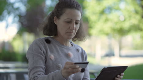 mujer madura alegre con tarjeta de crédito y tableta