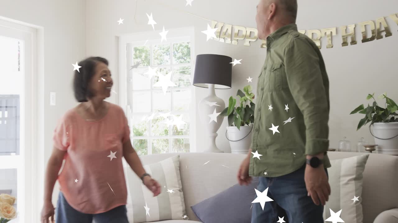 Man raising phone and woman leaning on sofa sparking confetti marking birthday banner showing tech