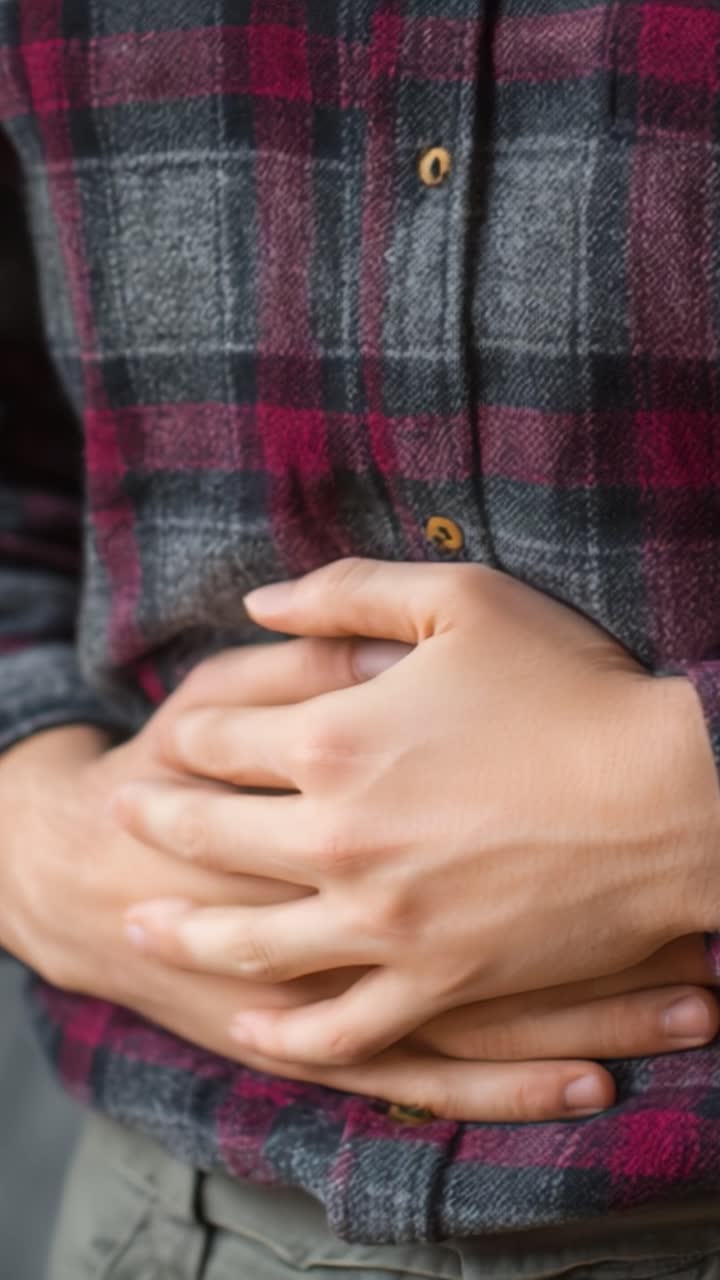 A Close-up View of a Person Holding Their Stomach, Capturing the Nuances of Discomfort and Physical Sensation in a Casual Setting