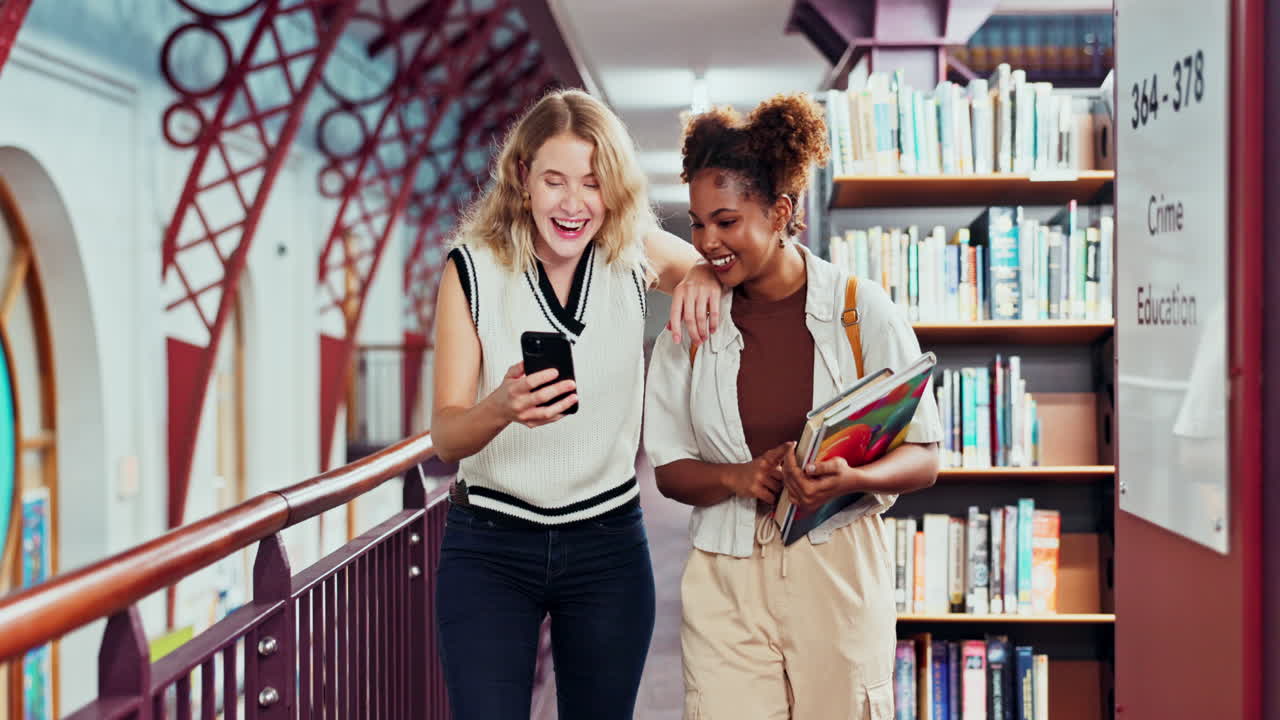 Due studenti in biblioteca che guardano un telefono
