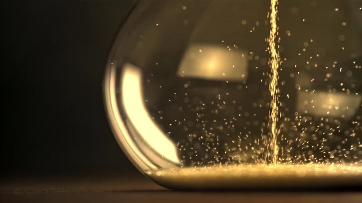 Golden Sand Falling in an Hourglass on a Dark Background