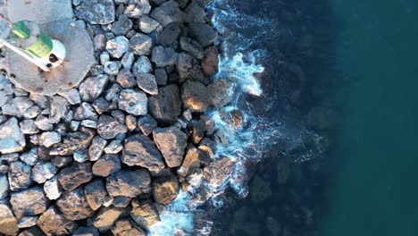 Una-Vista-Aérea-De-Las-Olas-De-Un-Dron-Rompiendo-Contra-Las-Rocas-En-Una-Playa-Al-Atardecer