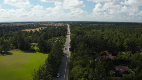 Aerial-shot-of-cars-driving-on-long-straight-road-in-countryside.-Panoramic-footage-of-flat-landscape.-Denmark