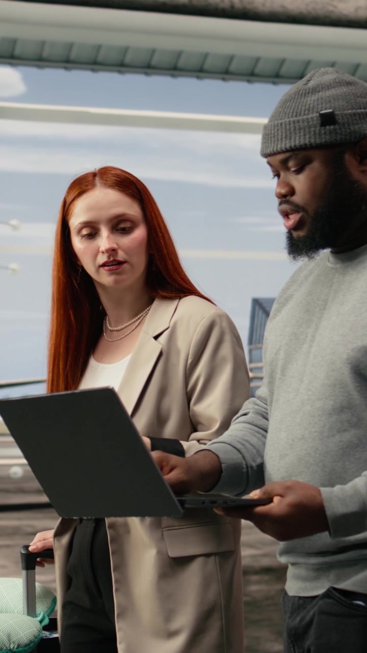 Vertical video Group of travelers walking in airport terminal, using laptop