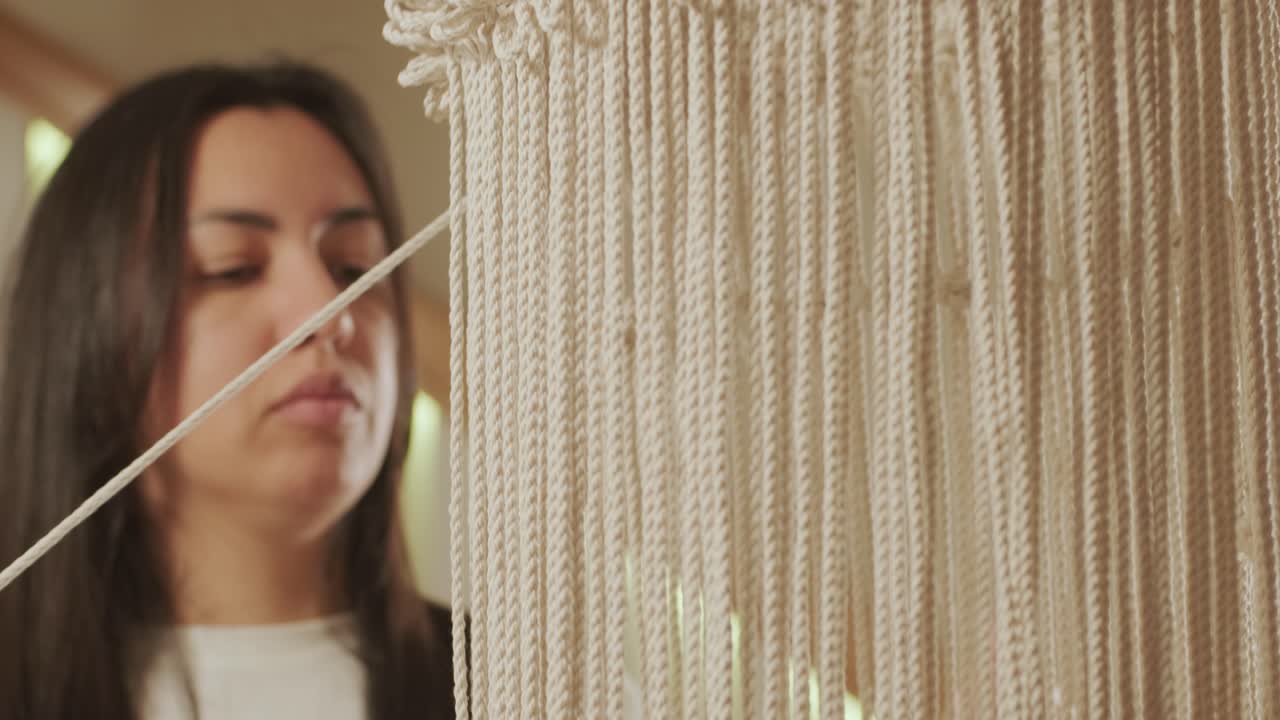 el hobby del hogar, tejer macrame. las manos de las mujeres tejen un adorno con hilos gruesos.