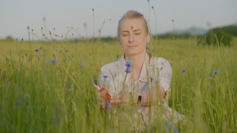 happy woman preparing bouquet of blue cornflowers in meadow