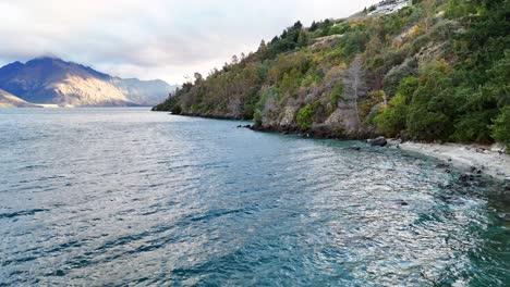 aerial footage of lake wakatipu's tranquil waters and lush shoreline in queenstown, new zealand, under soft, natural lighting