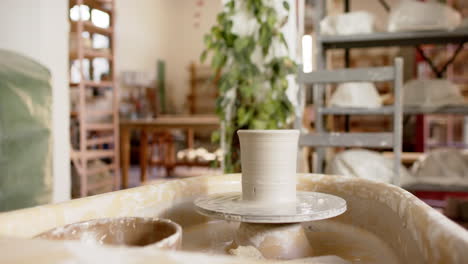 potter's wheel with clay vase in pottery studio