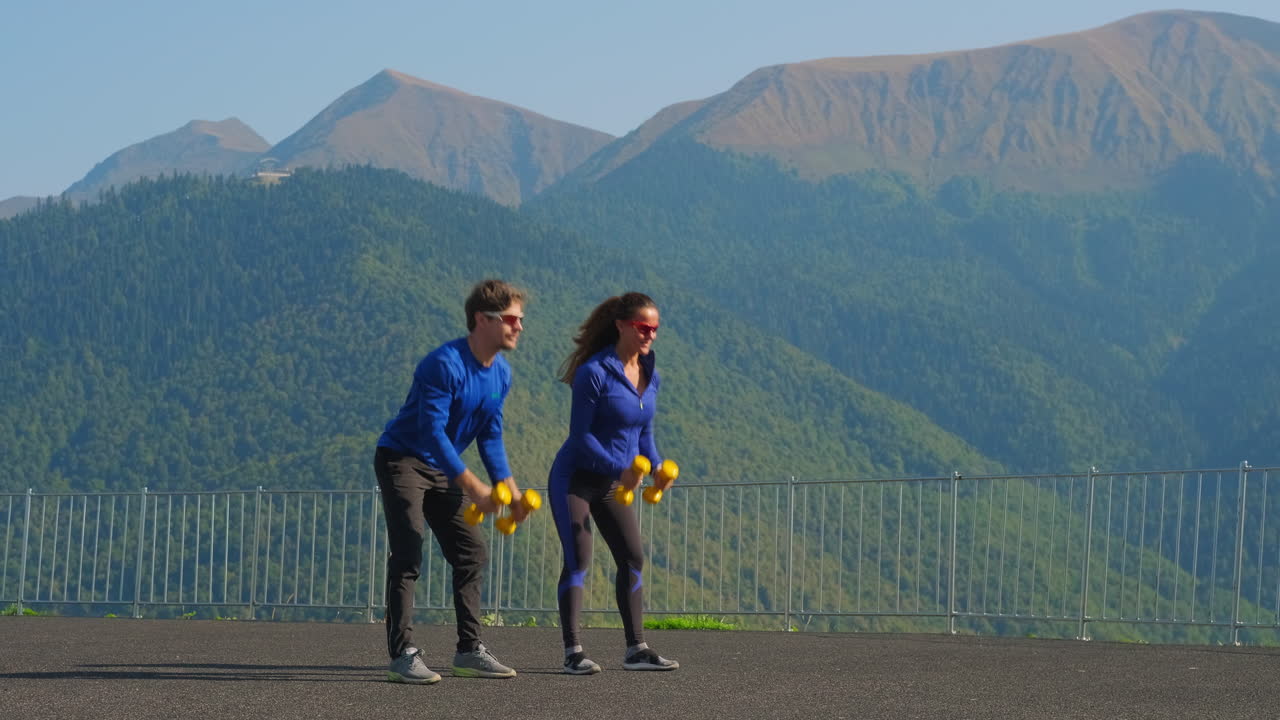 pareja haciendo ejercicio con pesas en las montañas
